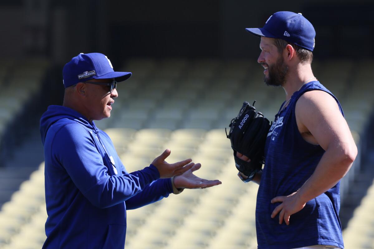 Dodgers manager Dave Roberts, left, talks with pitcher Clayton Kershaw during a workout at Dodger Stadium on Thursday.