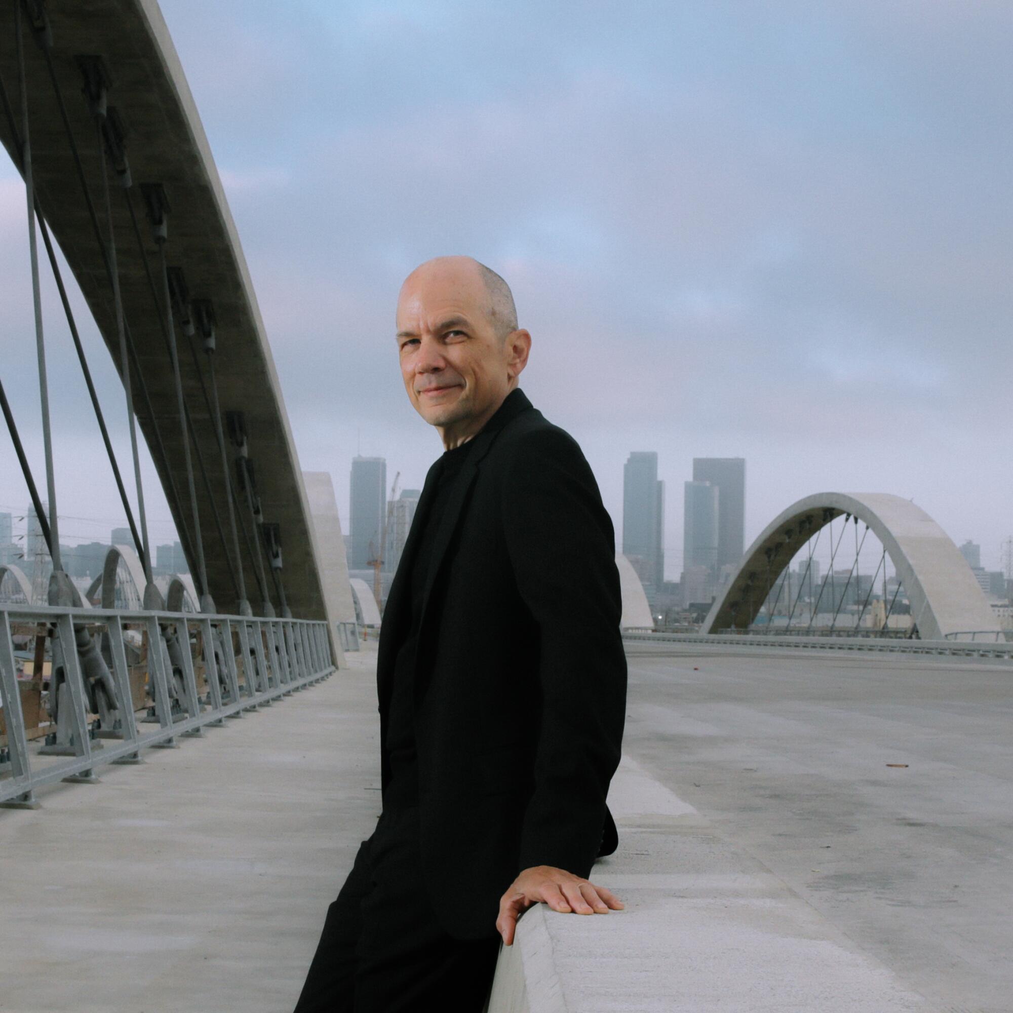 A man leans on a concrete barrier outdoors.