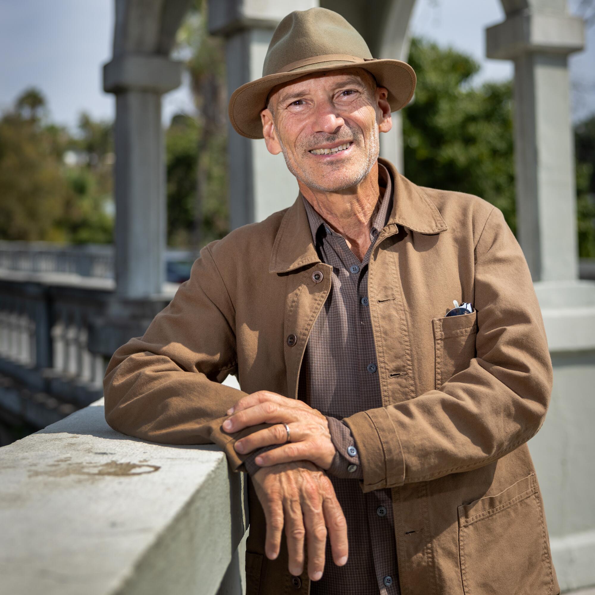 A man in a hat leans on a bridge.