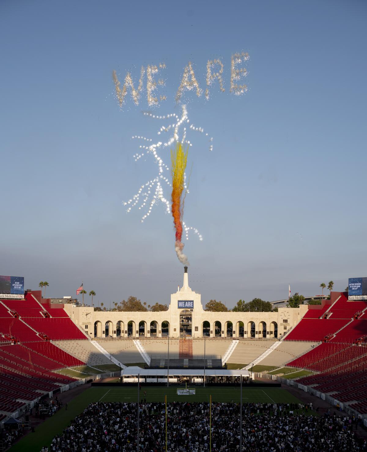 Chalk-based fireworks spell out "We Are" above the Los Angeles Memorial Coliseum.