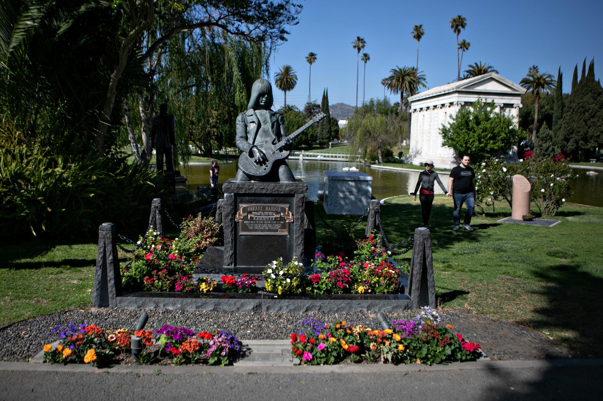 People walk by musician Johnny Ramone's grave during a visit to the Hollywood Forever Cemetery