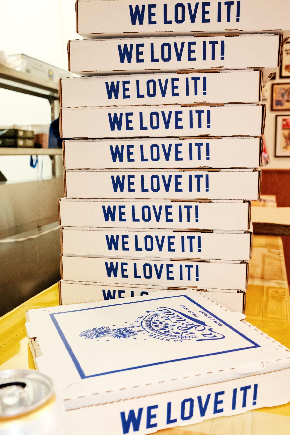 A stack of blue-and-white pizza boxes that say "WE LOVE IT!" at LaSorted's pizzeria in Chinatown