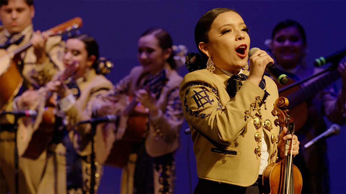 A woman sings in a mariachi band.