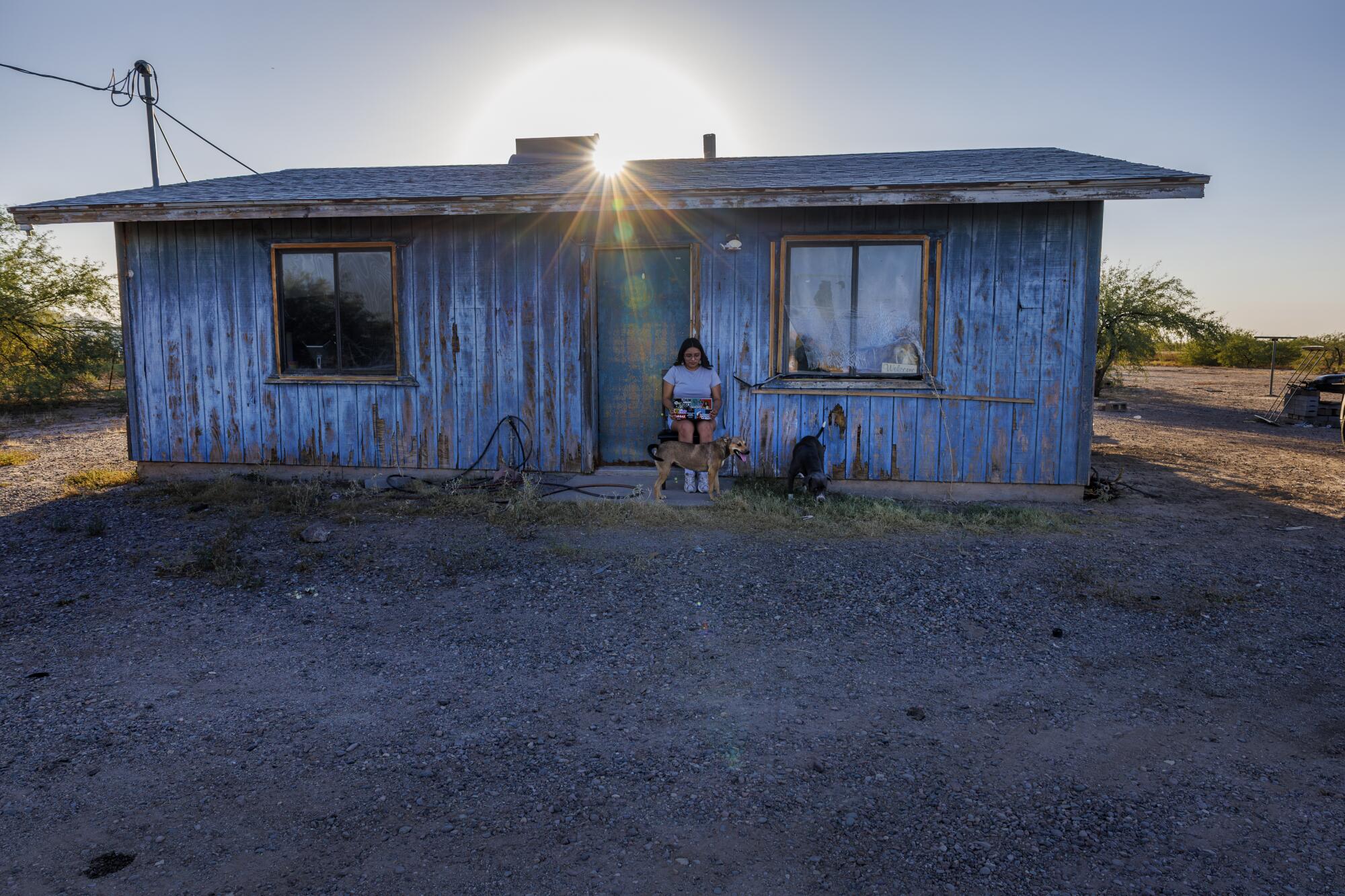 Gila River tribal member Susanna Osife finds a shady place in front of her home to work on her computer.