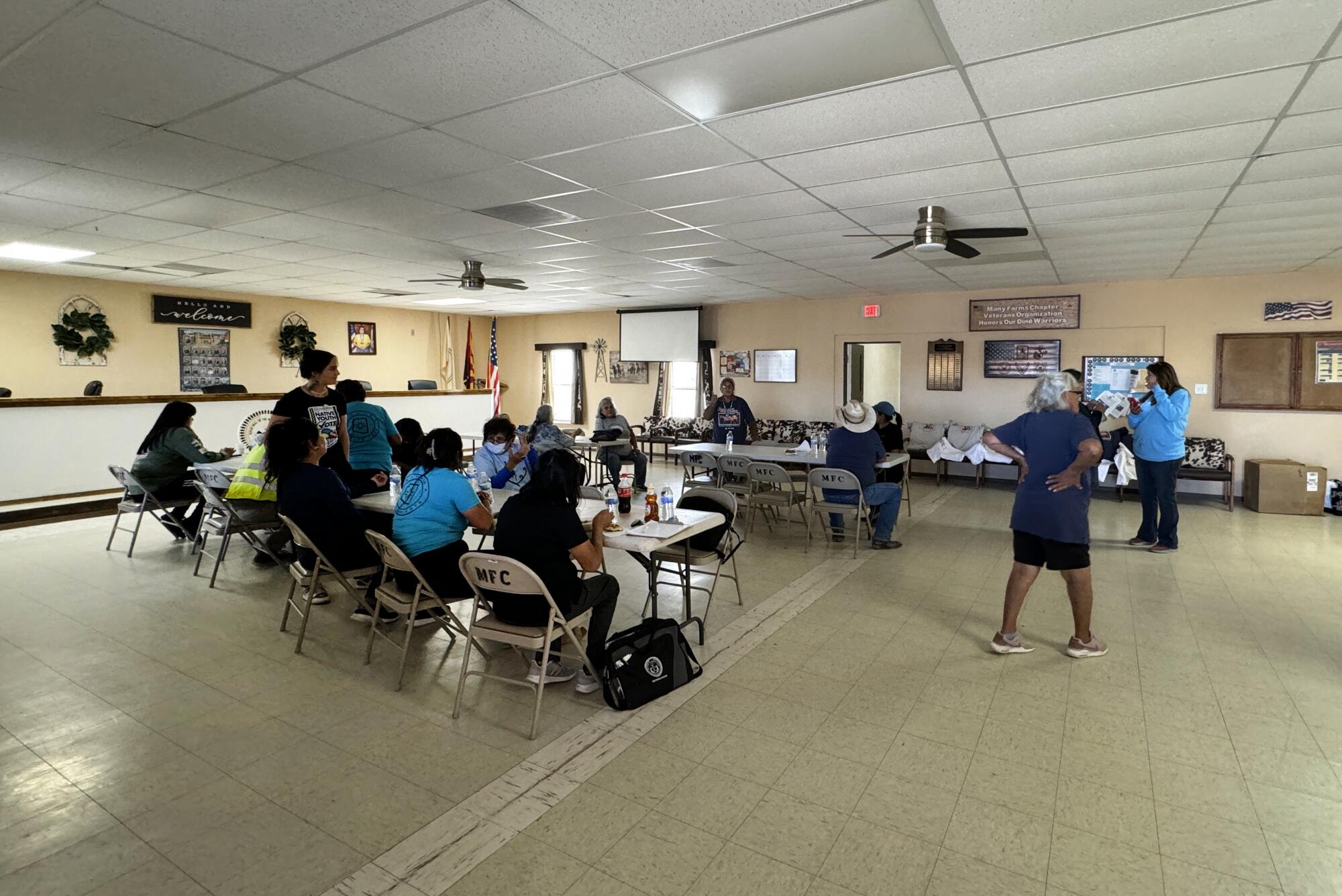 People sit at tables during a voter registration drive.