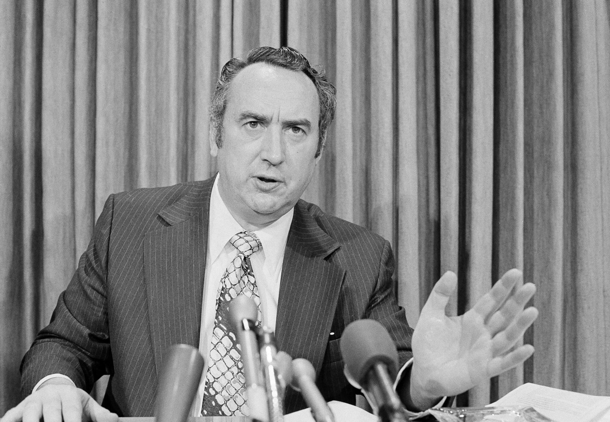 A black-and-white photo of Congressman Phillip Burton speaking during a press conference  