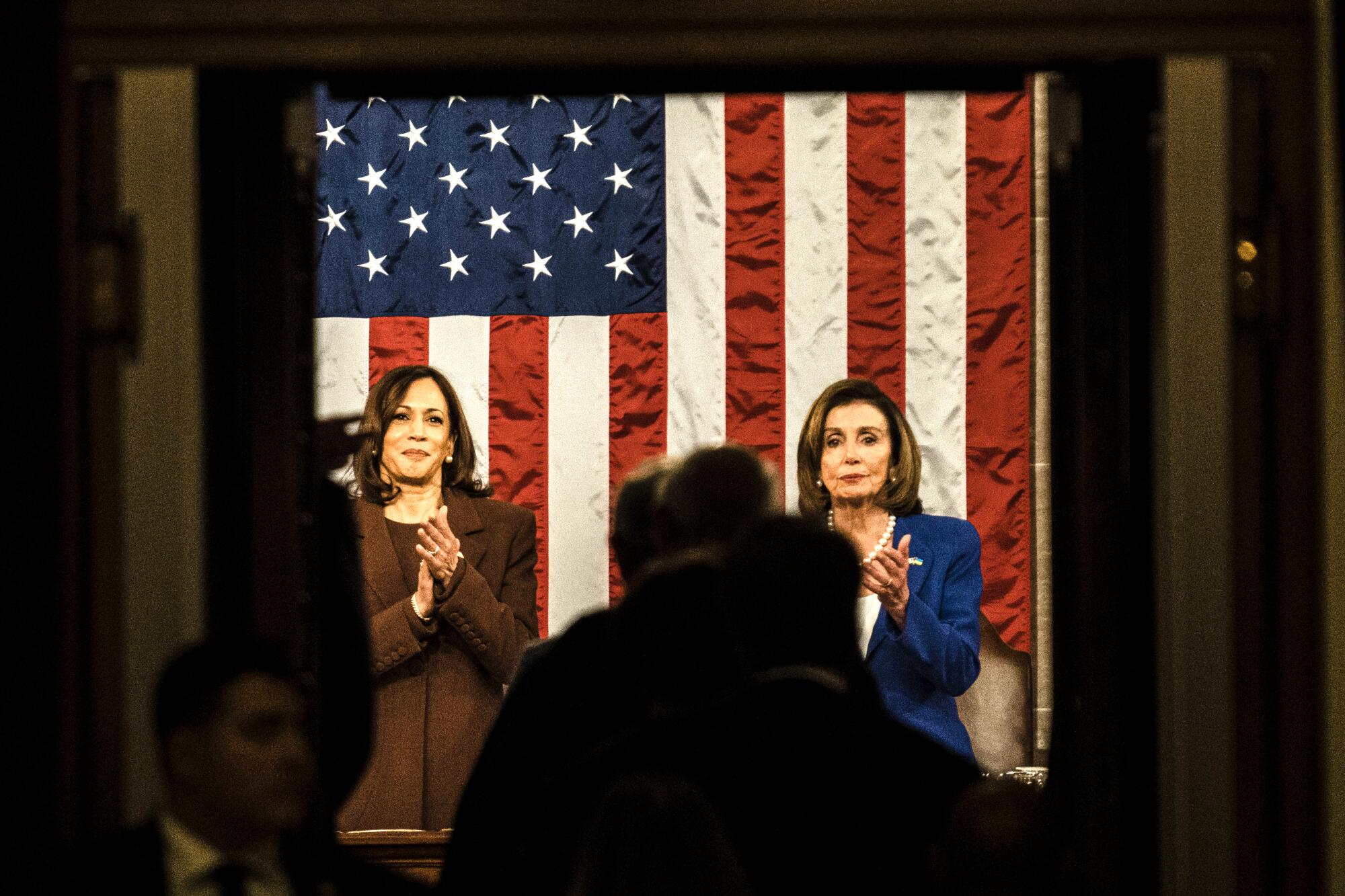 Vice President Kamala Harris and Speaker of the House Nancy Pelosi stand side by side in the House chamber.