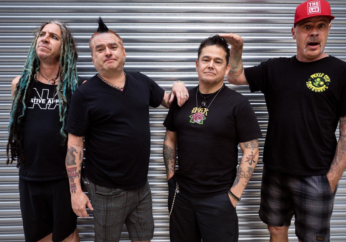 Four punkers standing in front of a metal door