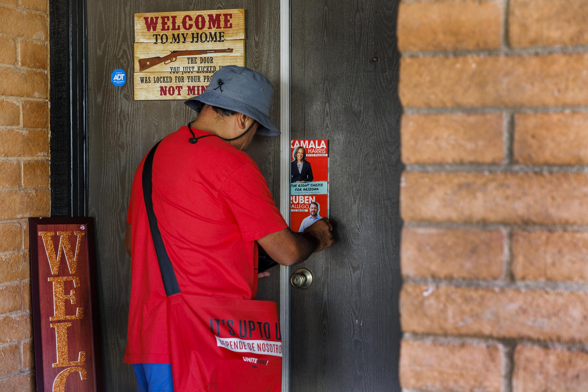 Canvasser Jose Manuel hangs a pamphlet for Kamala Harris and U.S. Senate candidate Ruben Gallego in Glendale, Ariz.