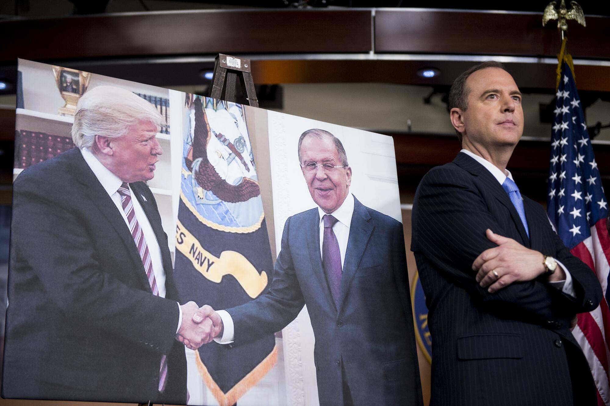 Rep. Adam Schiff stands next to a photo of Donald Trump shaking hands with Russian Foreign Minister Sergey Lavrov.