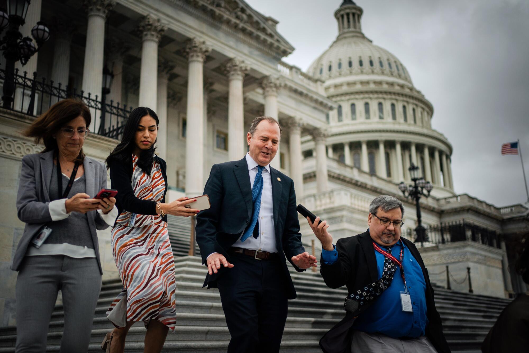 Adam Schiff and reporters walk down the steps outside the House of Representatives.