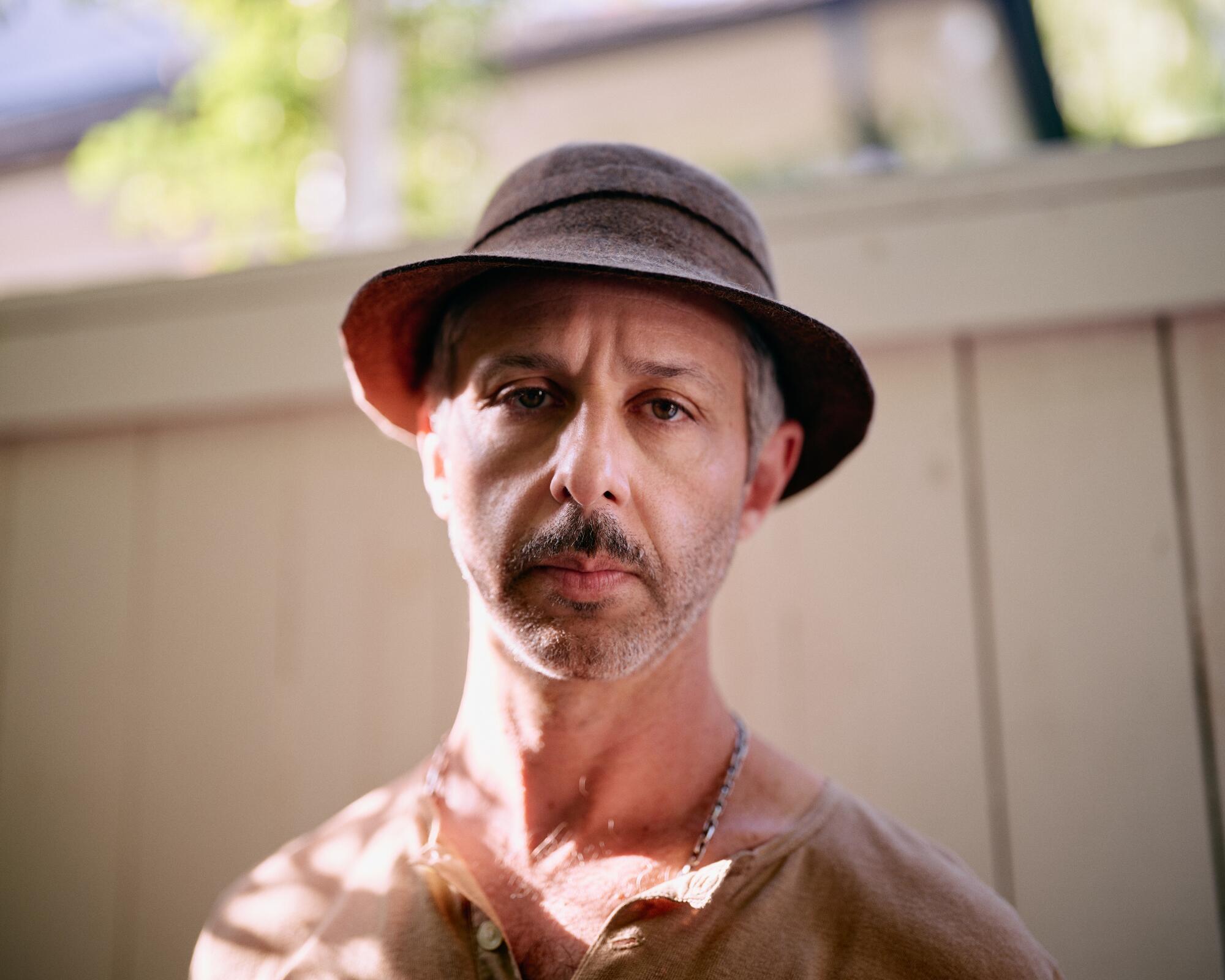 An actor in a hat looks into the lens.