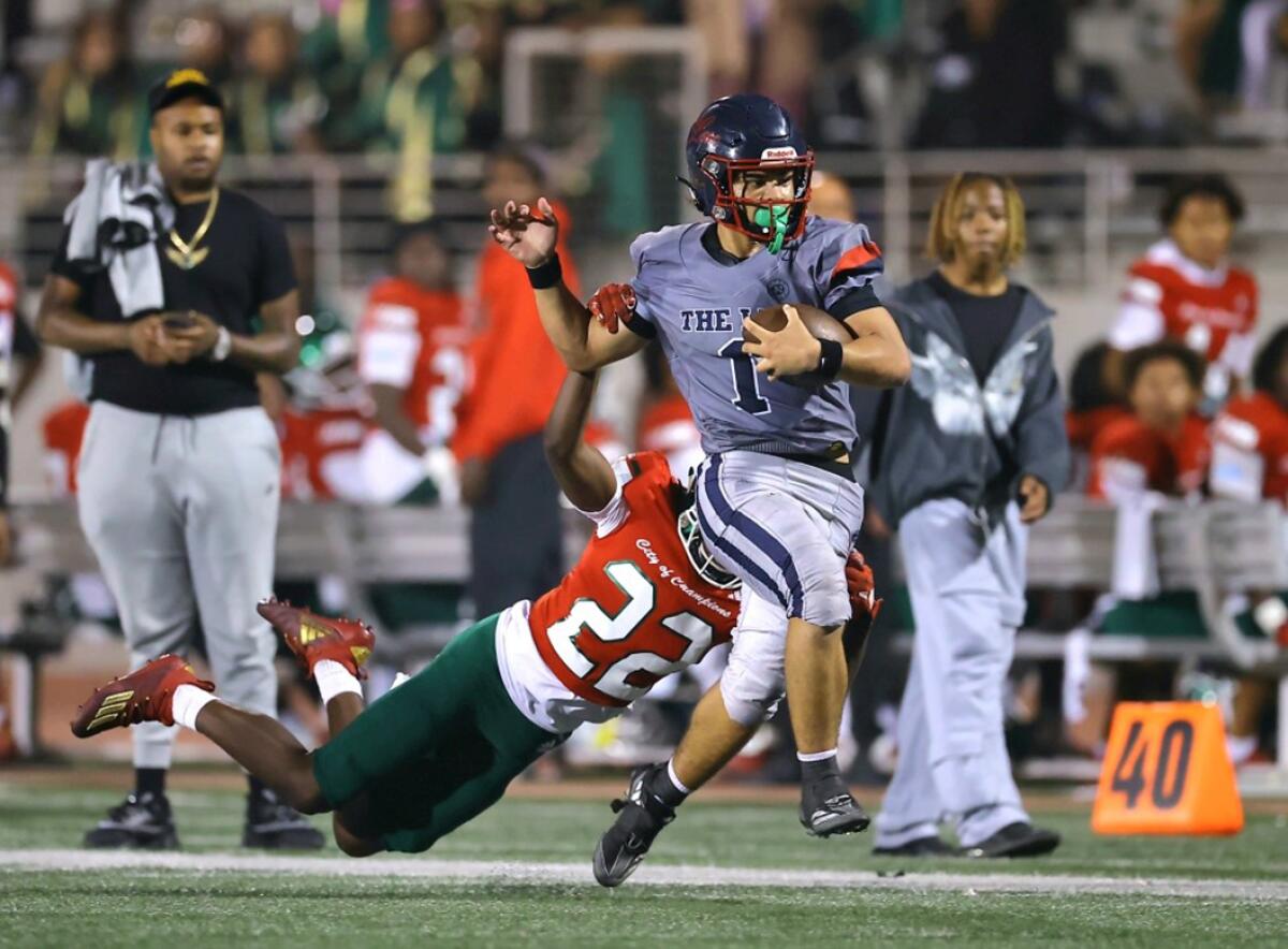 Leuzinger High running back Journee Tonga tries to slip a tackle by Inglewood defender Noah Clark on Friday night.