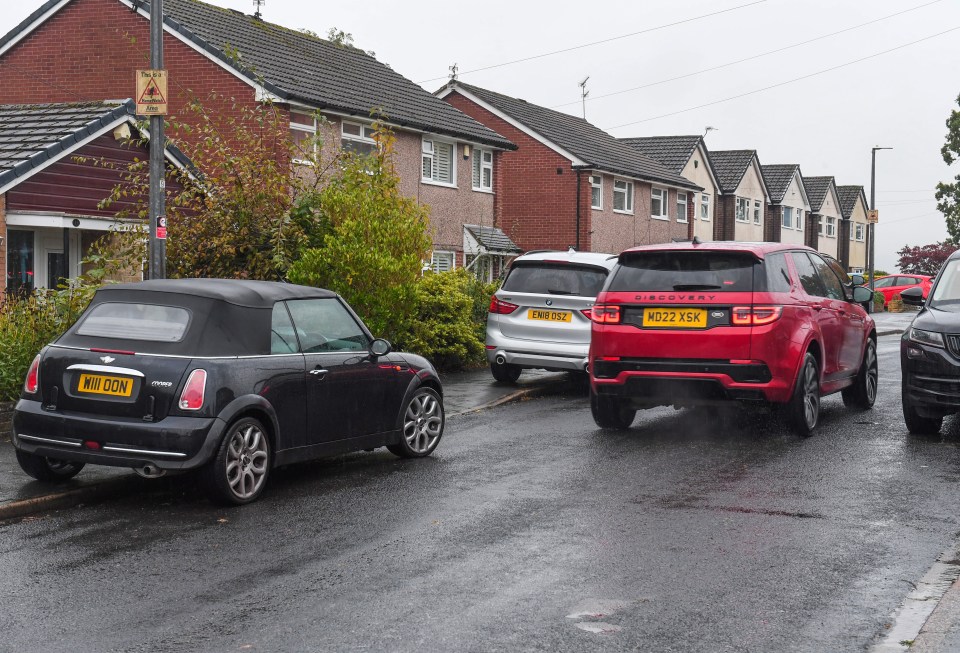 Cars seen parked on the curb close to the school