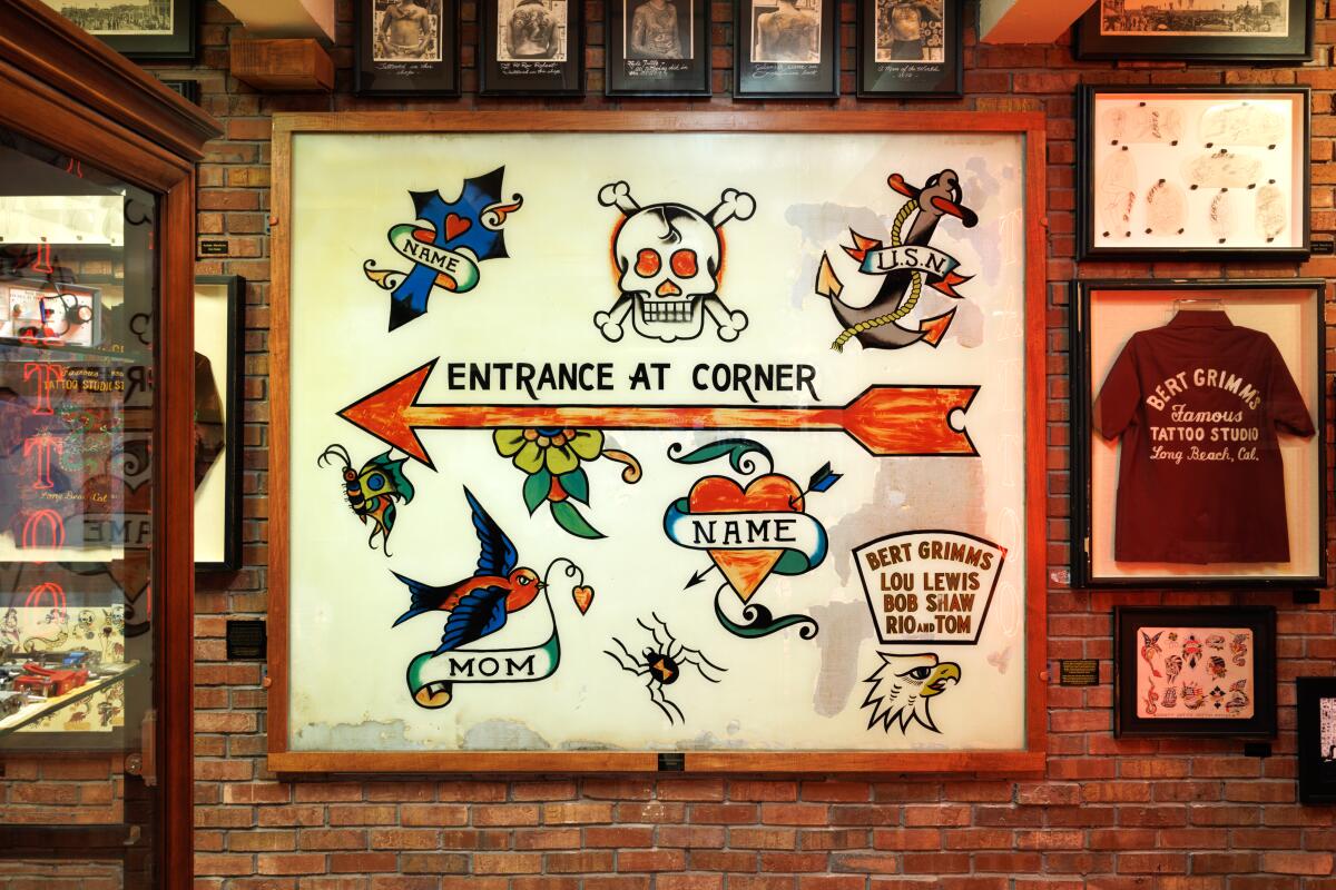 A sign indicates "Entrance at corner" among tattoo designs at Outer Limits Tattoo and Museum.