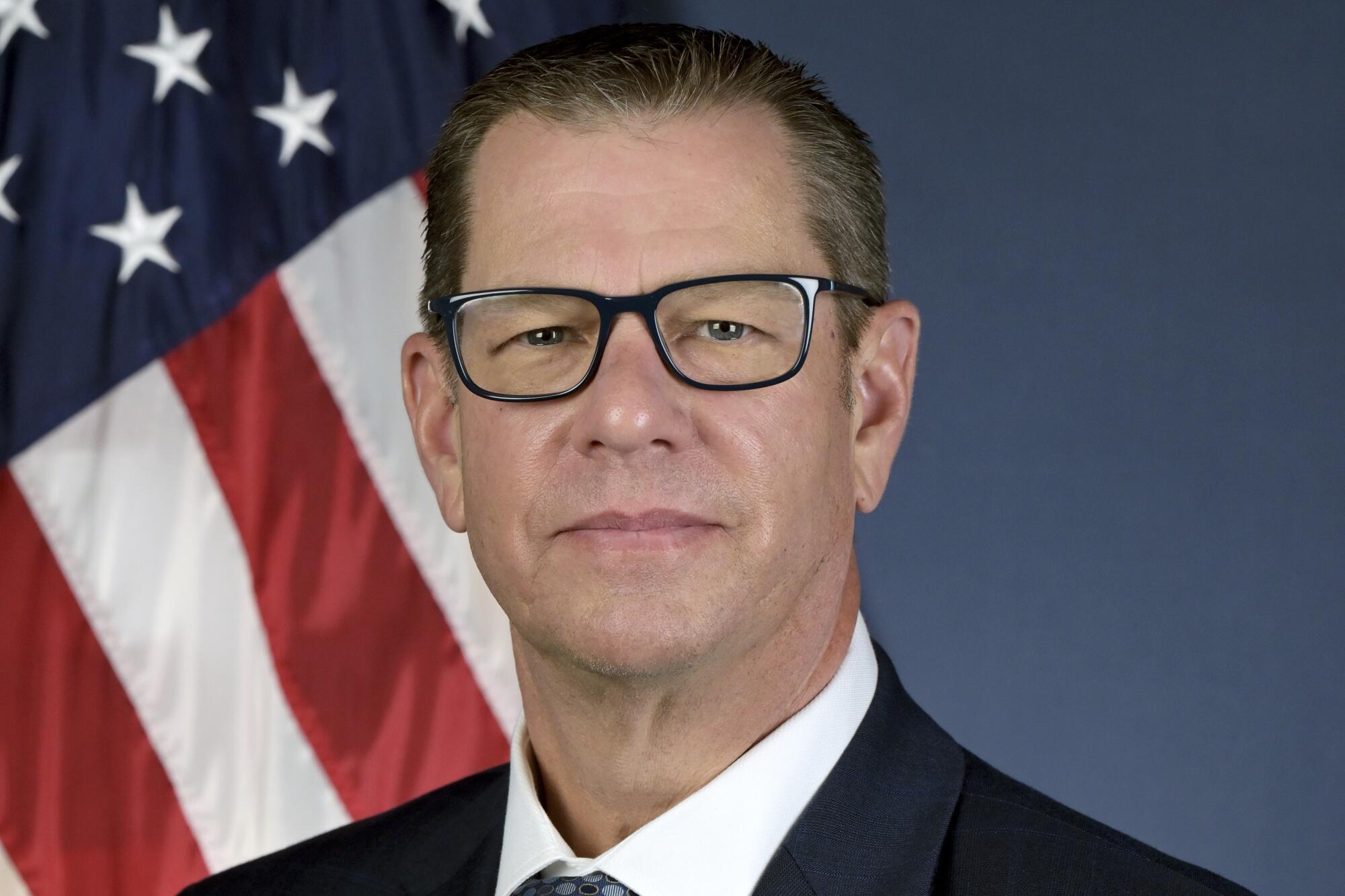 CARB chief Steven Cliff, wearing glasses and a suit, is in front of an American flag.