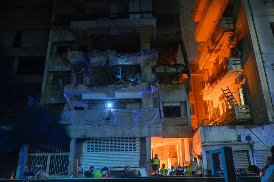 People gather in front of a damaged building after the hit