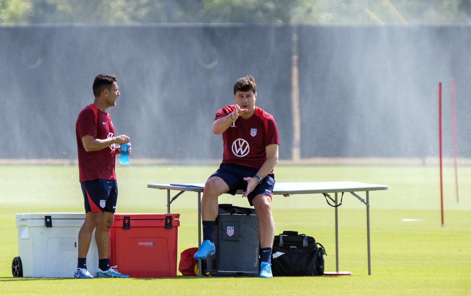 U.S. soccer coach Mauricio Pochettino and first assistant coach Jesus Perez wait for their player before training Friday