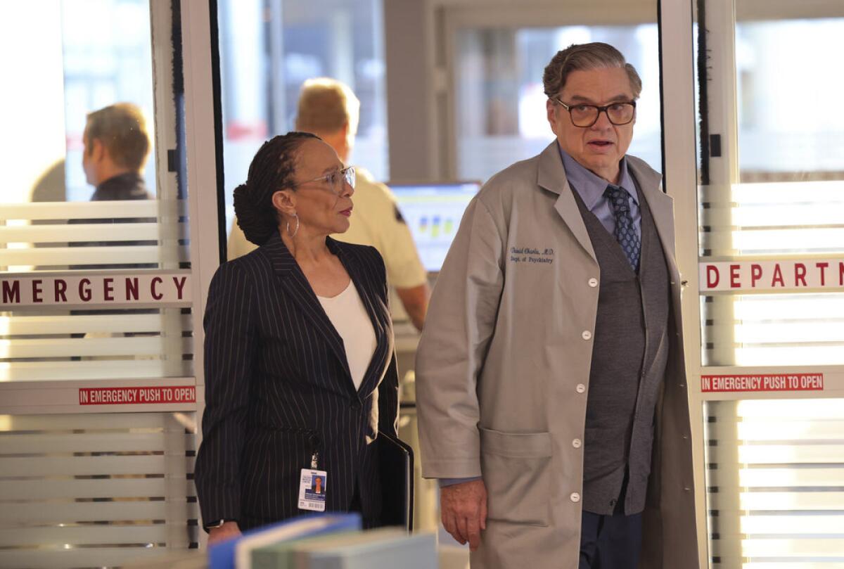 A woman and a man standing at the doors of an emergency room. 