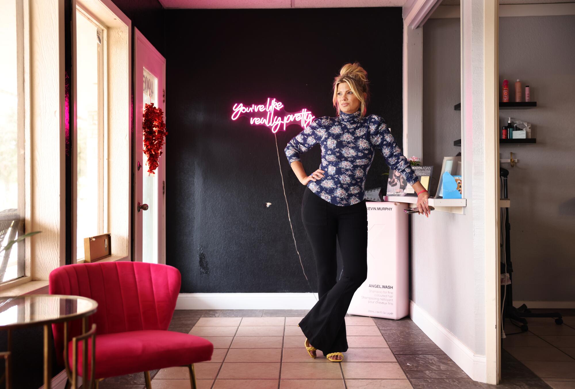 A woman stands next to windows in a salon 