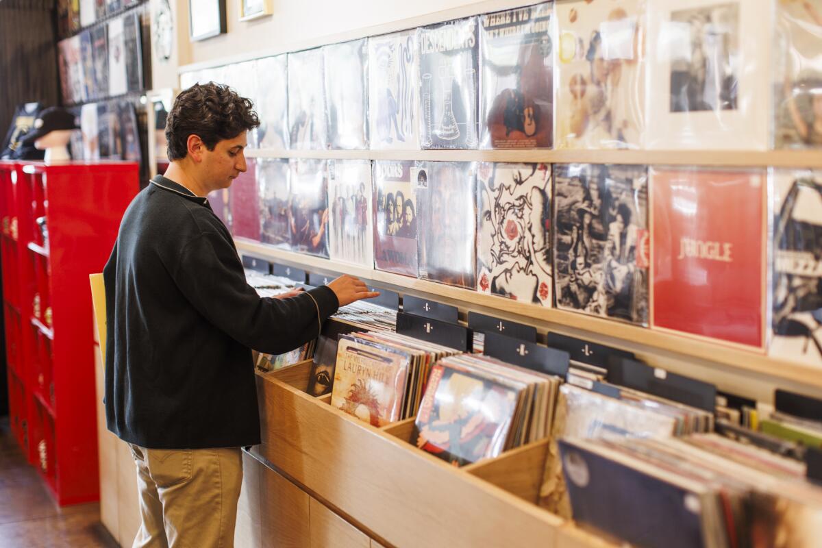 Man in a record store looking at vinyl albums in bins.