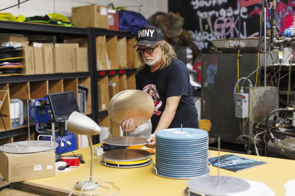 Man at a record pressing plant holding vinyl