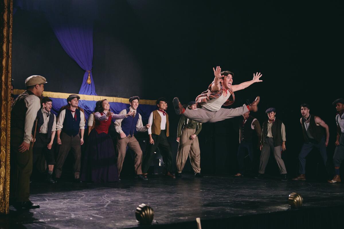 Performers watch a dancer leaping into splits during Broadway Votes' "Newsies" music video.