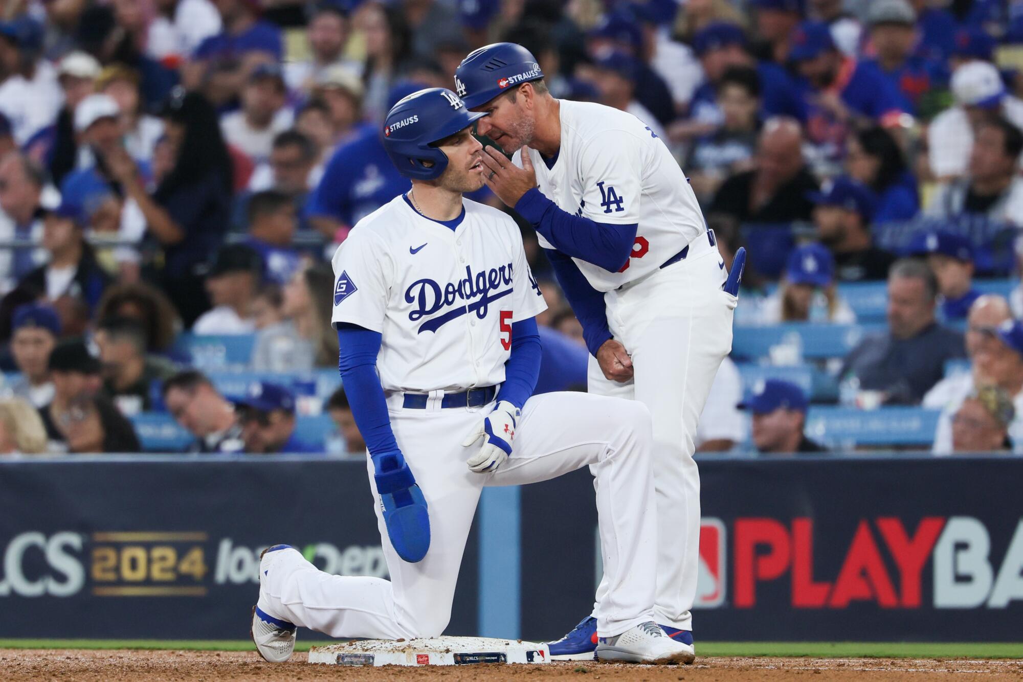 Dodger Freddie Freeman talks with first base coach Clayton McCullough after hitting a single during Game 1 of the NLCS