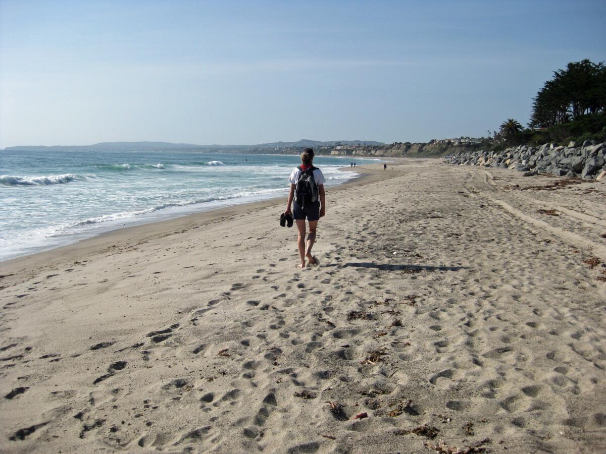 A lone hiker walks on San Clemente State Beach.