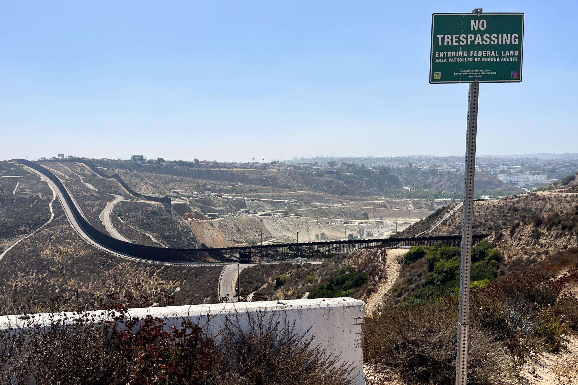 A "No Trespassing" sign is posted in a scrub-filled hilly setting