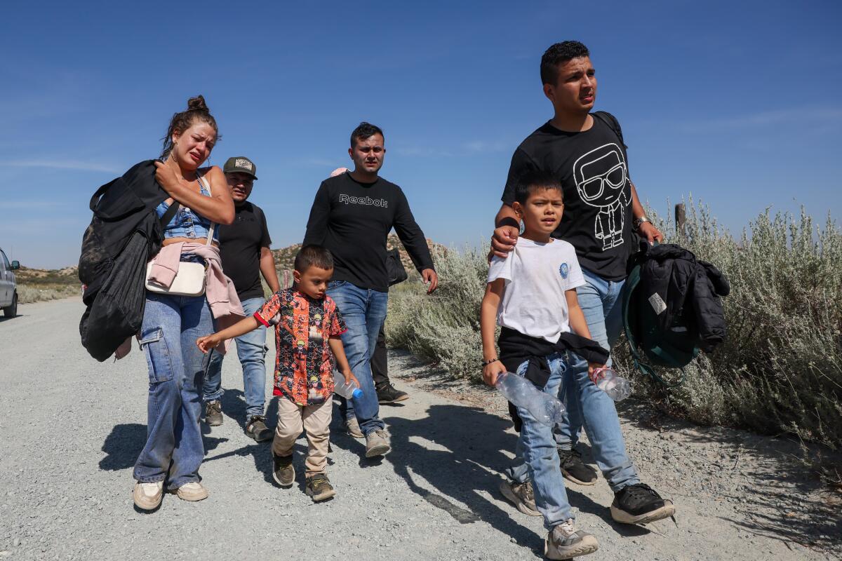 Men, a woman and children walk together in a rural area 