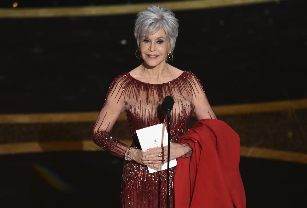 Jane Fonda holding an Oscars envelope onstage