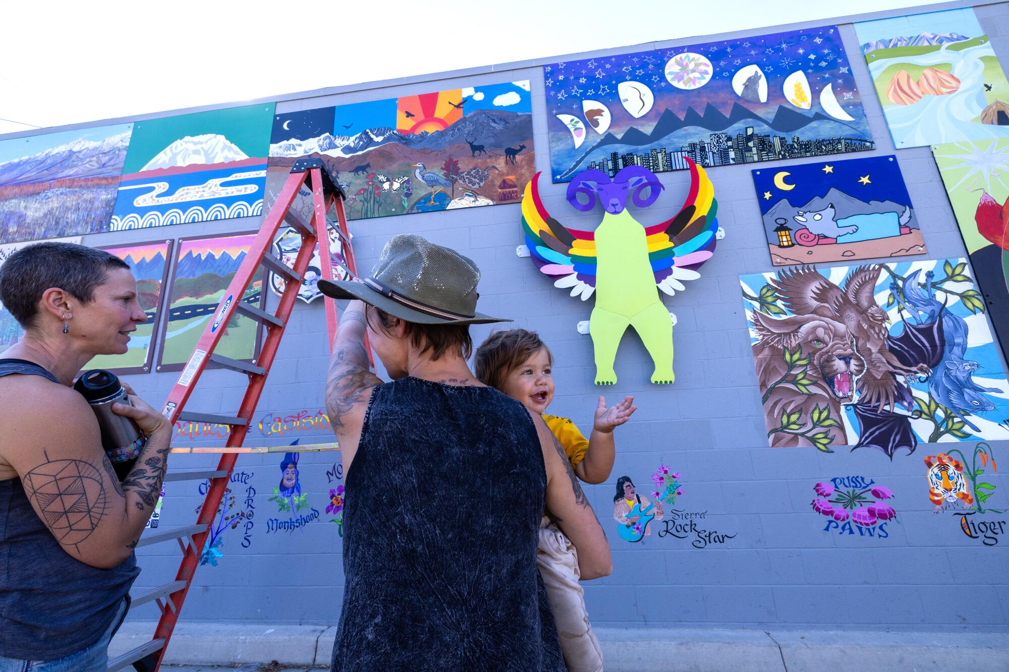 People stand near a colorful mural. 