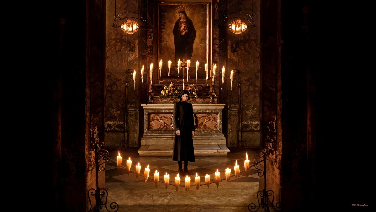 A woman stands amid candles.