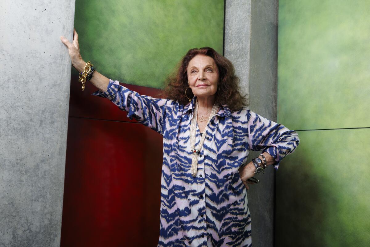 Diane von Furstenberg standing leaning one hand against a colorful wall