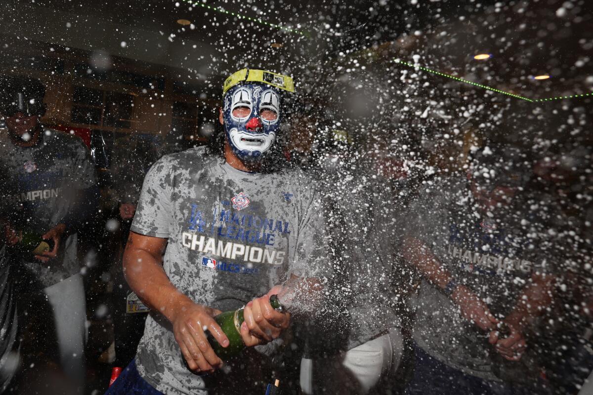 Dodgers pitcher Brusdar Graterol wears a mask while celebrating with teammates in the clubhouse.