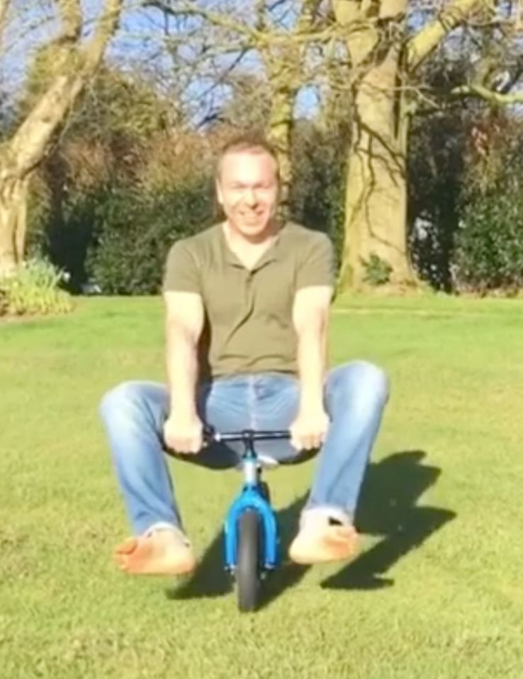 Sir Chris larks about on his son's push bike in the garden of the family home