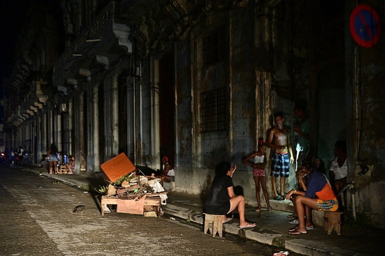 Cubans chat at night on a street during a nationwide blackout caused by a grid failure in Havana on October 18, 2024