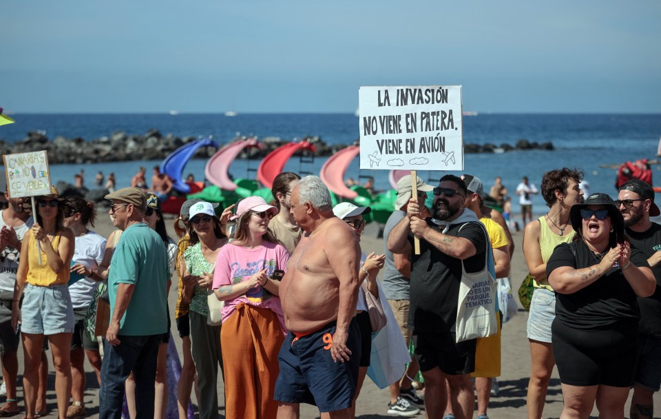 Flag-waving residents beat drums and blew whistles as they wandered along the shoreline in Playa de las Americas