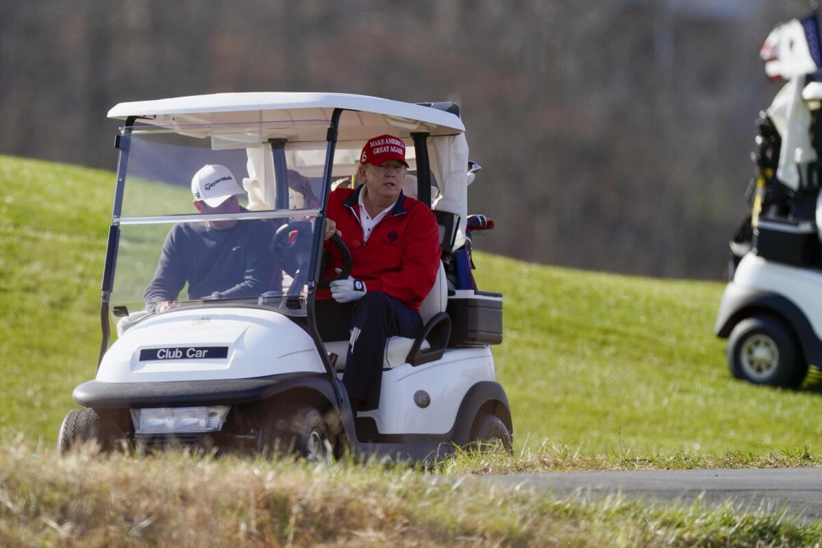 President Donald Trump drives a golf cart.