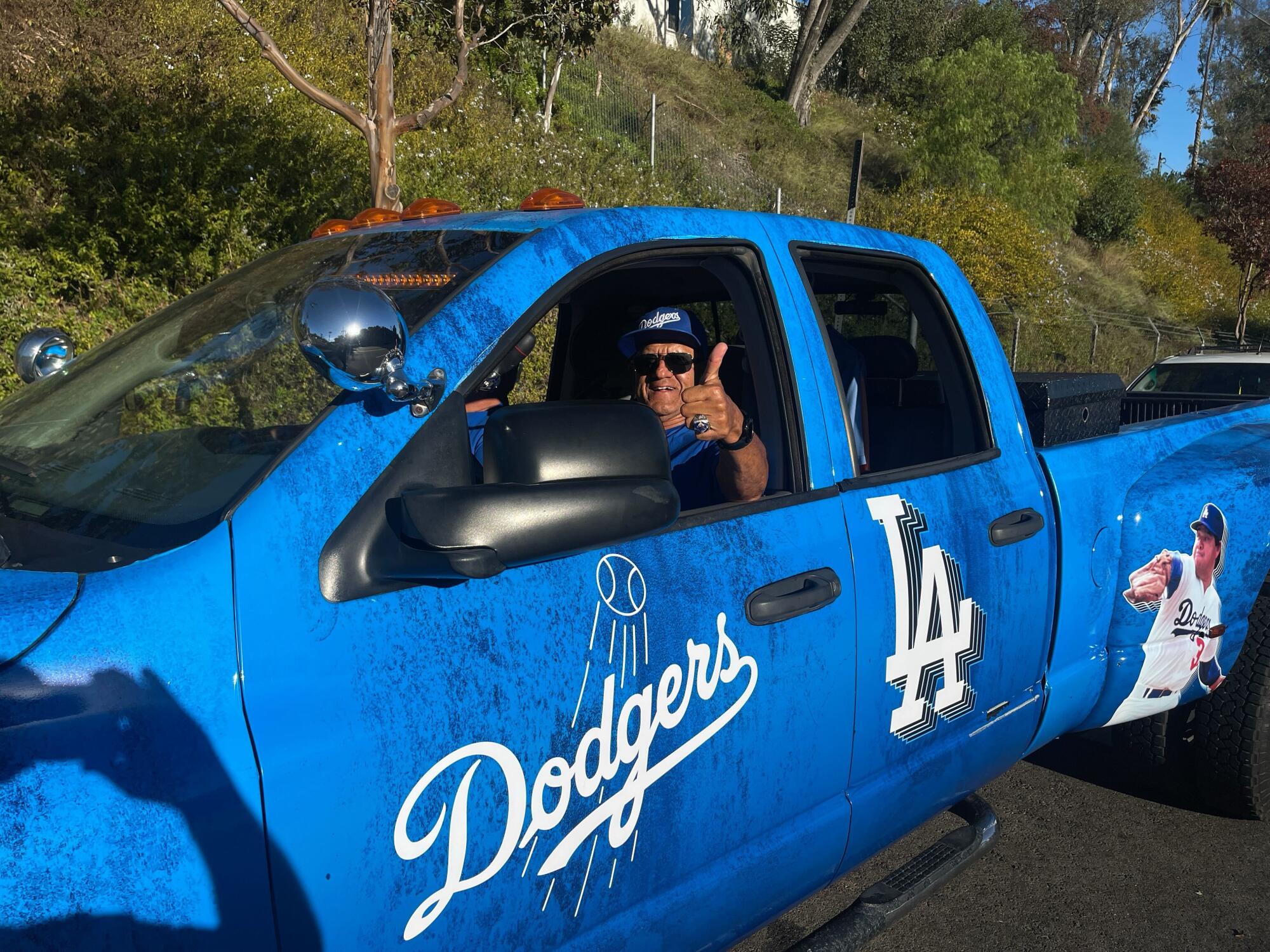 Manny Acosta sits in the “Dodger Dodge," a blue truck featuring the team's logo and Fernando Valenzuela pitching