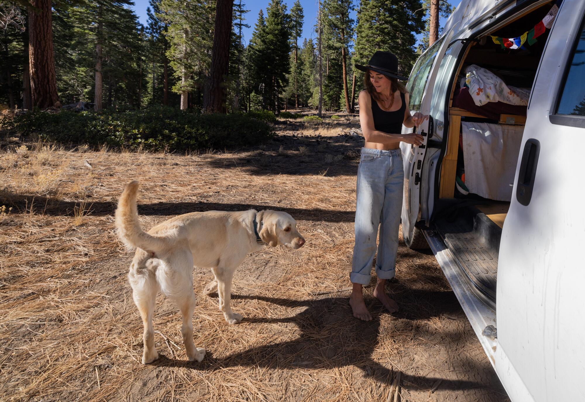 Emily Markstein, with a dog she is sitting for a friend, outside her van in the Inyo National Forest.