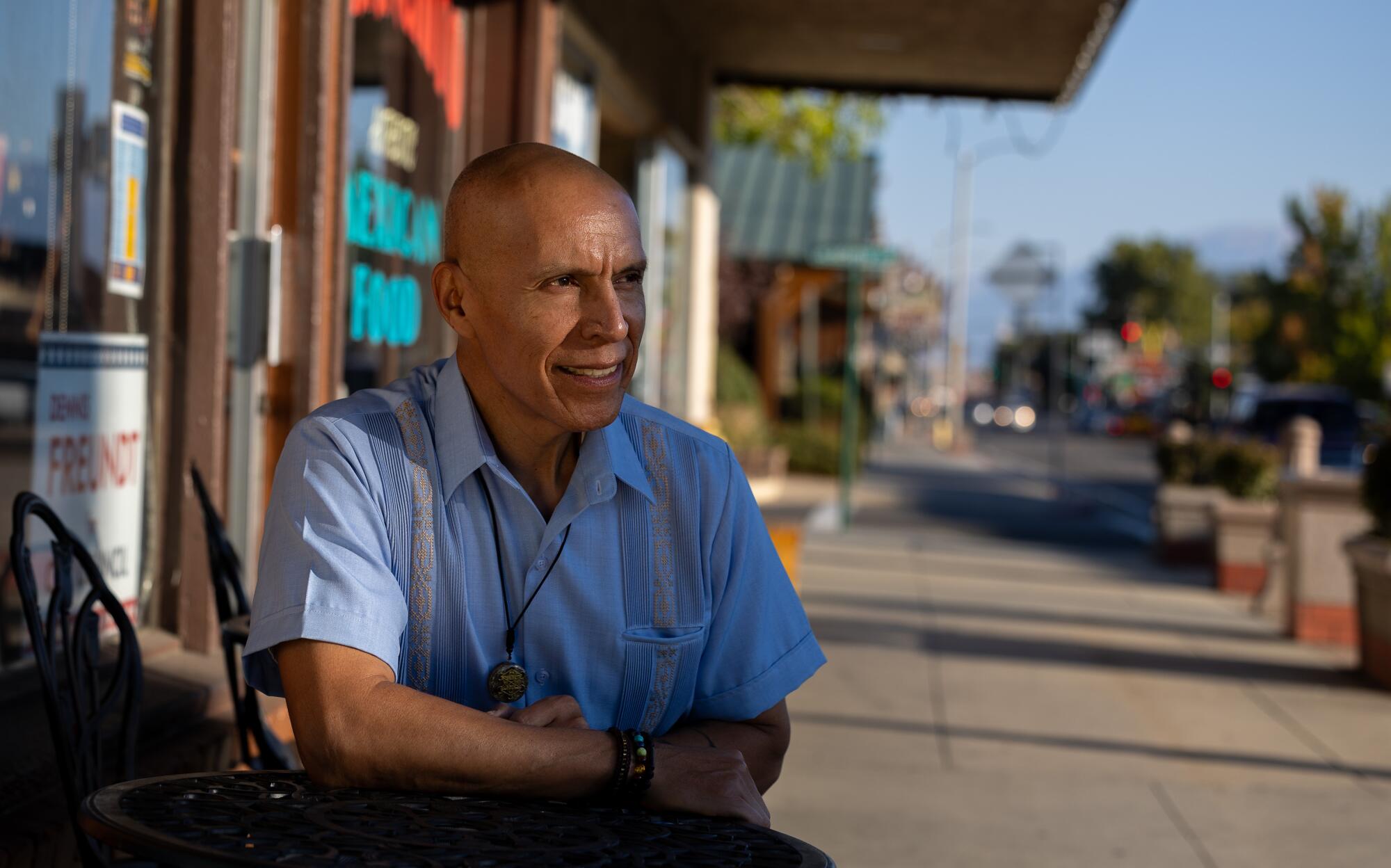 Bishop Mayor Jose Garcia sits on a sidewalk along Main Street in Bishop.