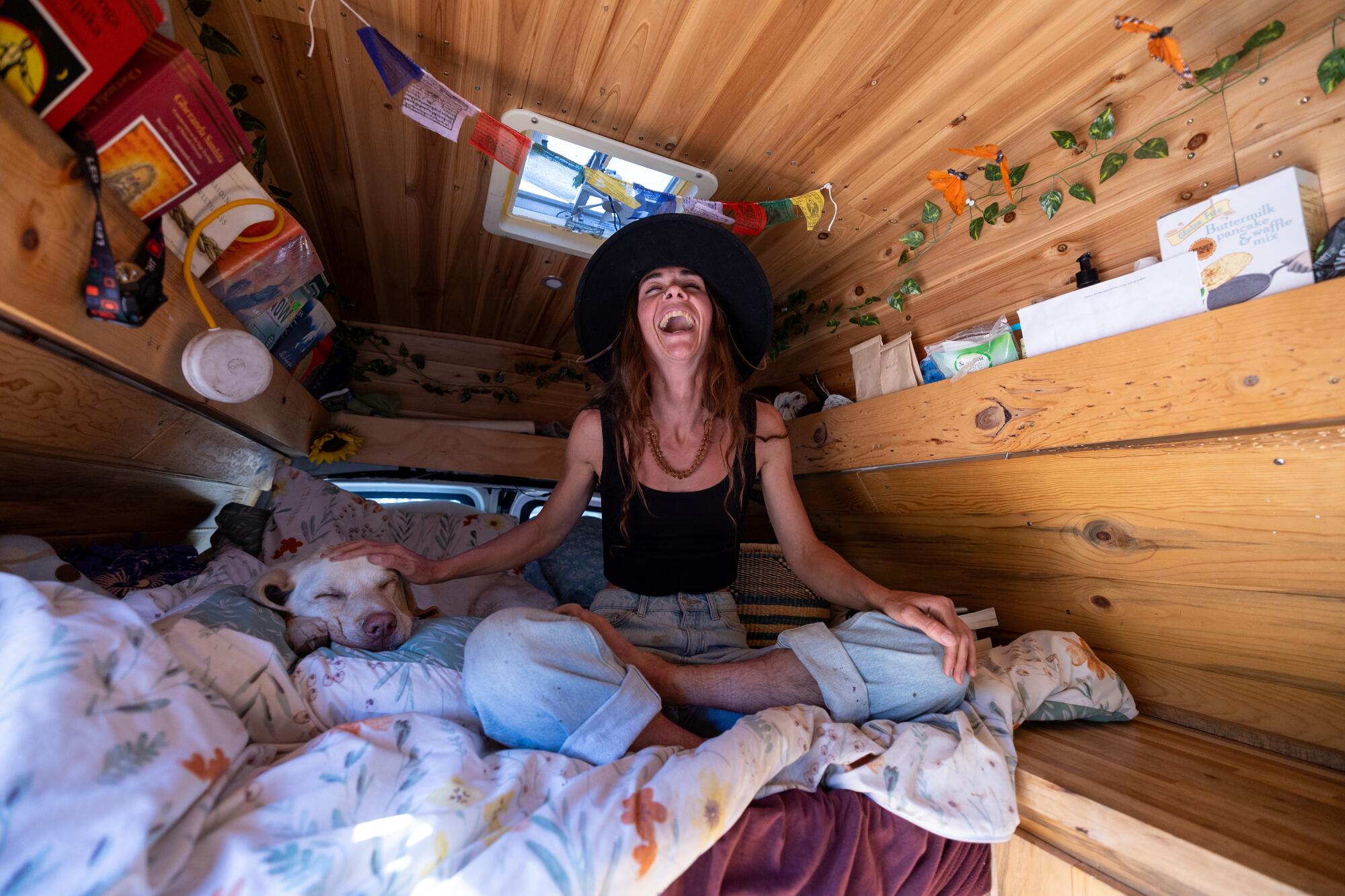 Emily Markstein laughs sitting on a mattress inside her van.