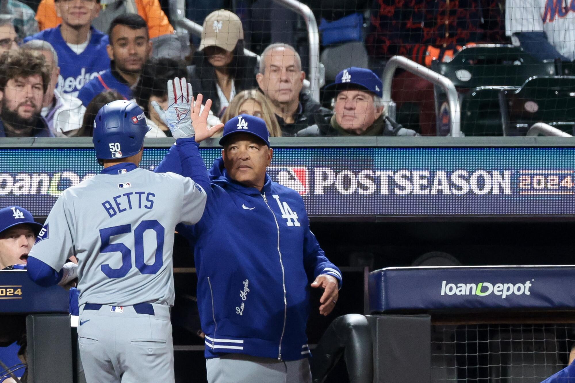 Mookie Betts celebrates with manager Dave Roberts in the dugout after scoring on an RBI single in Game 4 of the NLCS.