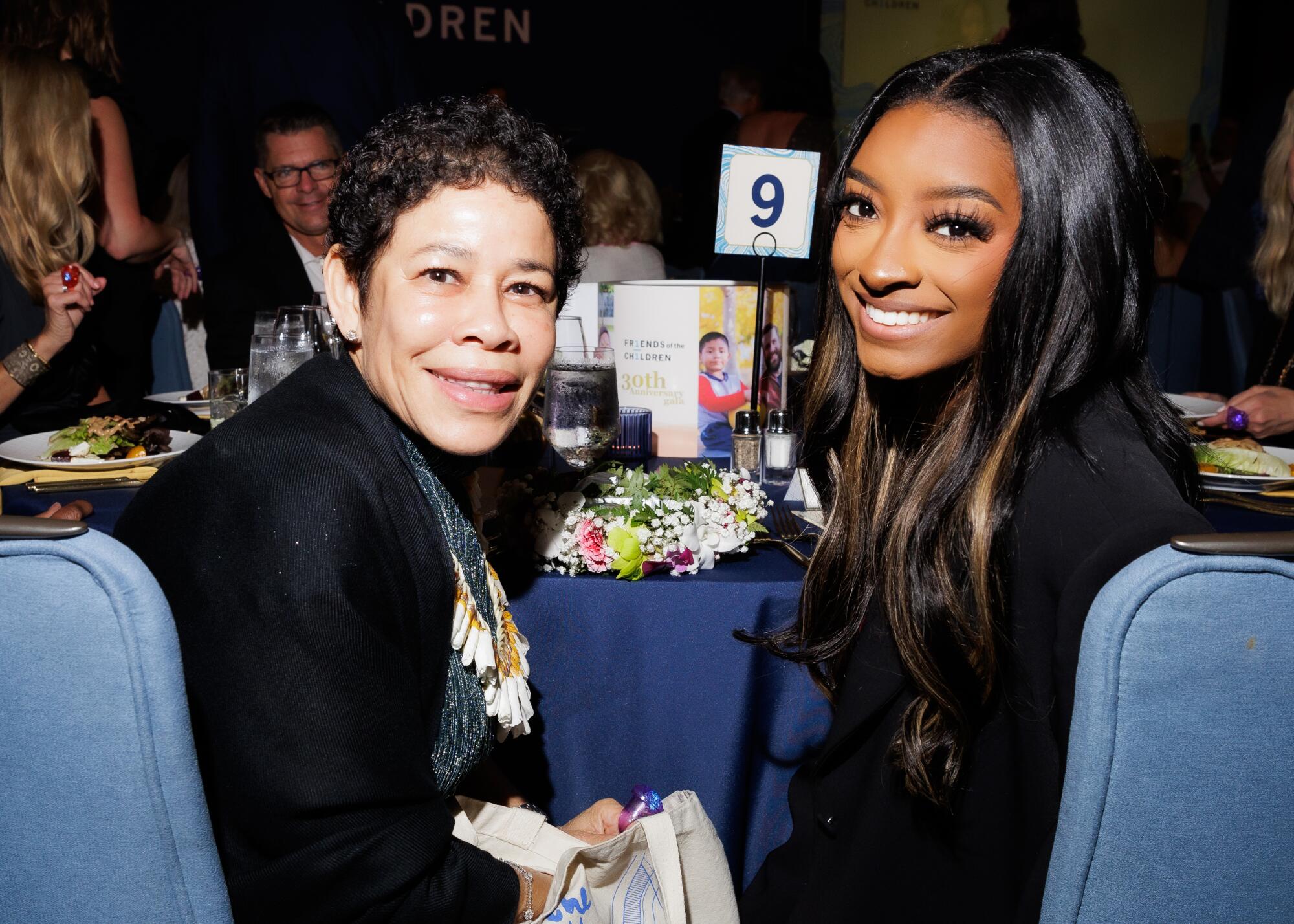 Nellie and Simone Biles sit at a table during the Friends of the Children 30th anniversary gala