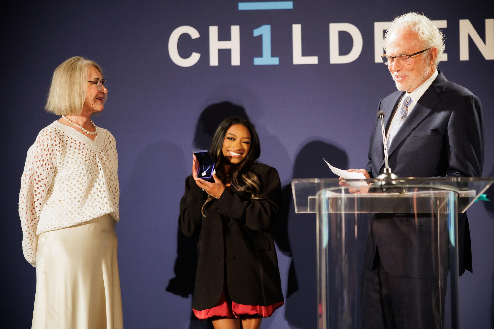 Longtime Friends of the Children supporters Christine and Gary Rood present Simone Biles with a custom necklace