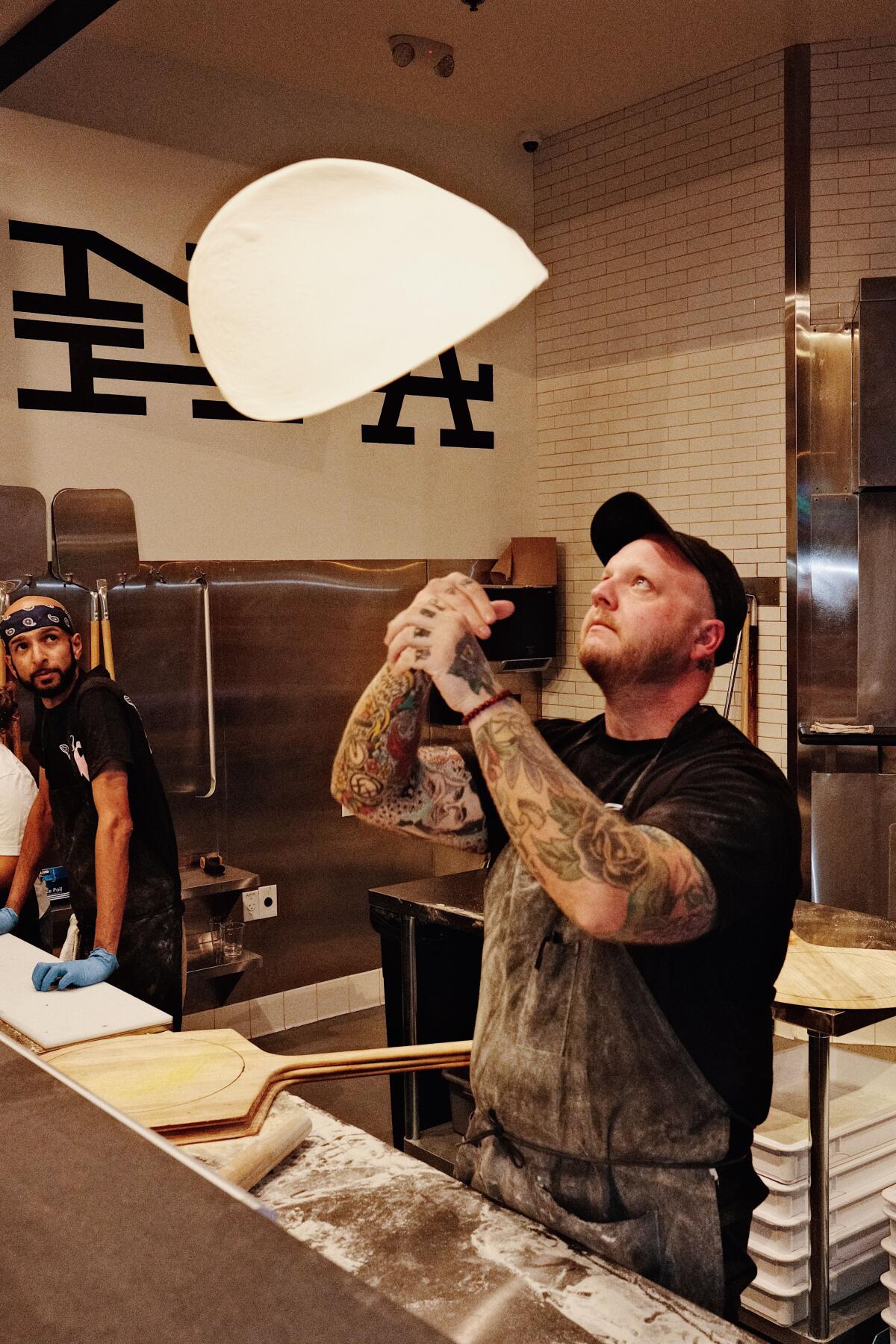 Founder Chris Wallace tosses pizza dough into the air in the open kitchen of Ozzy's Apizza in North Hollywood.