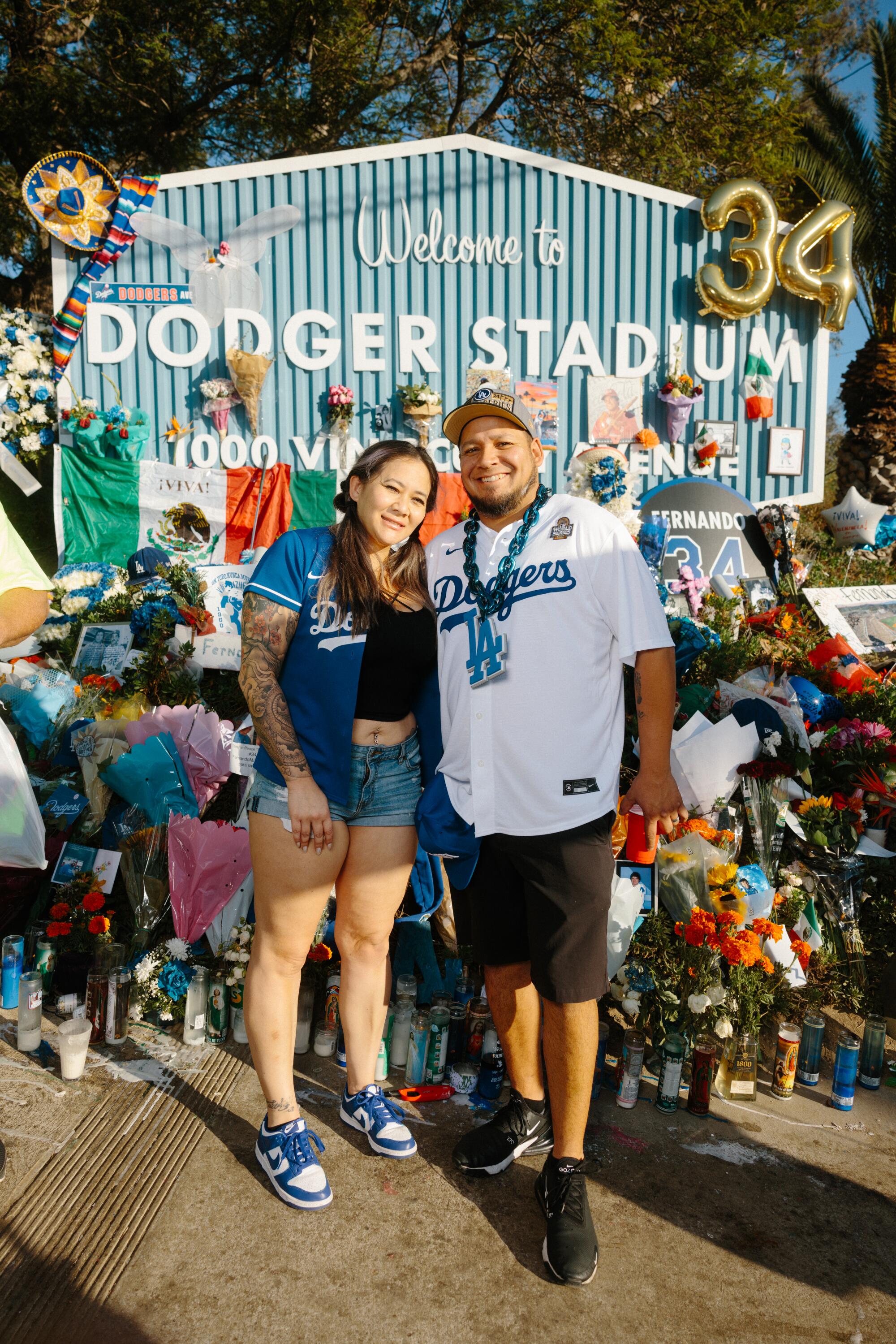  Jennifer and Miguel Guerrero in Dodgers shirts in front of flowers at Dodger Stadium