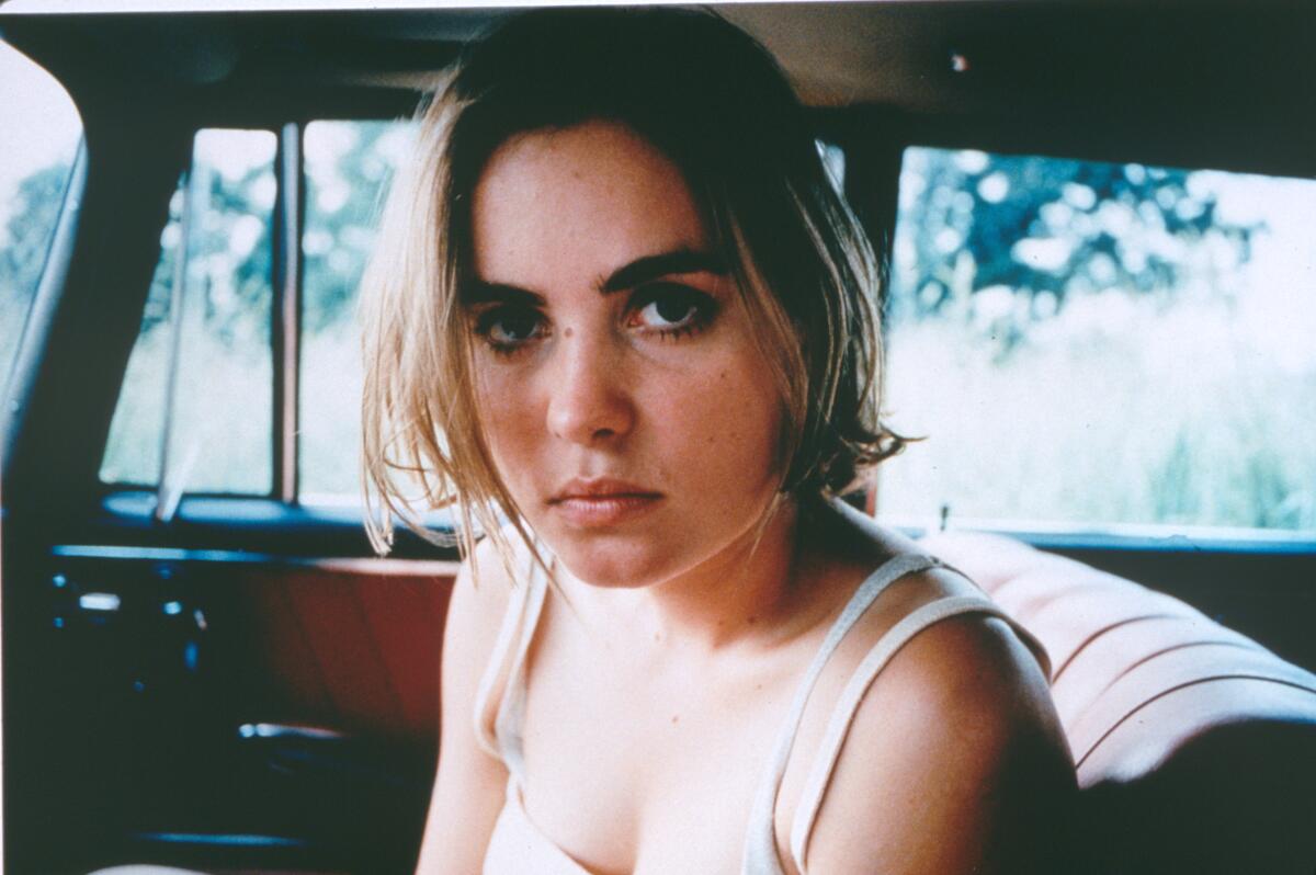 A woman sits in the passenger seat of a car.